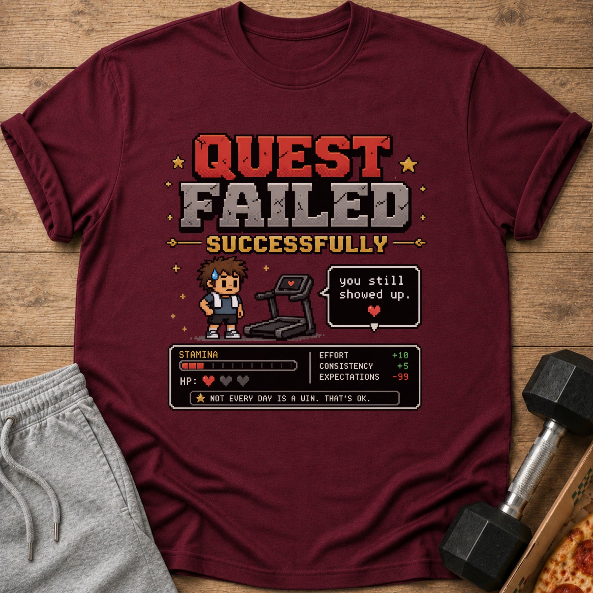 Maroon t-shirt with pixel art saying "QUEST FAILED SUCCESSFULLY" and fitness stats.