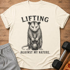 T-shirt with a possum lifting a kettlebell and text "LIFTING AGAINST MY NATURE."