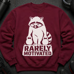 Maroon sweatshirt with white graphic of raccoon holding kettlebells and text "RARELY MOTIVATED".