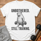 White t-shirt with a capybara holding dumbbells and text: "UNBOTHERED. STILL TRAINING."