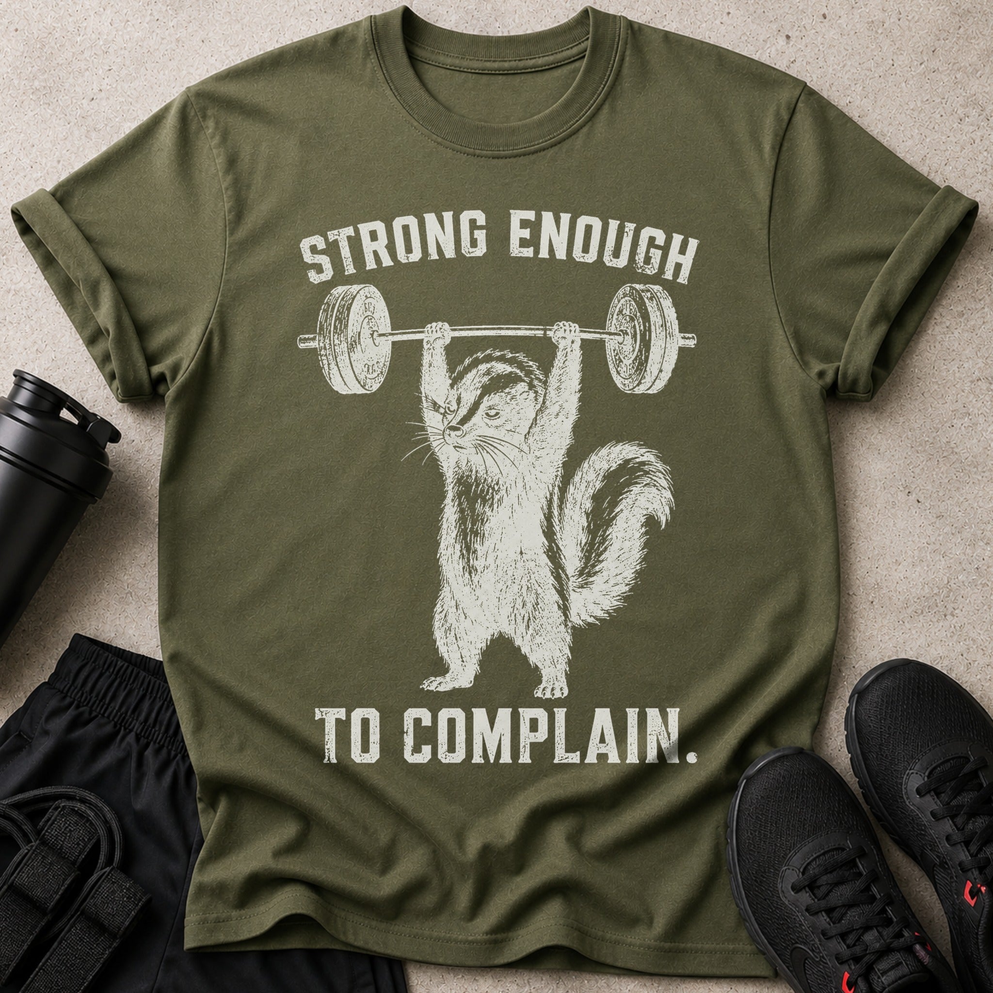 Olive green t-shirt with squirrel lifting barbell and text "Strong Enough To Complain."