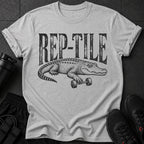 Grey t-shirt with black graphic text "REP-TILE" and a crocodile lifting a barbell.