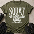 Military green t-shirt with distressed white "SQUAT" text and Bigfoot lifting weights.