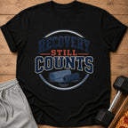 Black t-shirt with "Recovery Still Counts" text and gym equipment graphic.