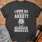 Dark grey t-shirt with text "I WORK OUT SO MY ANXIETY HAS BIGGER MUSCLES".