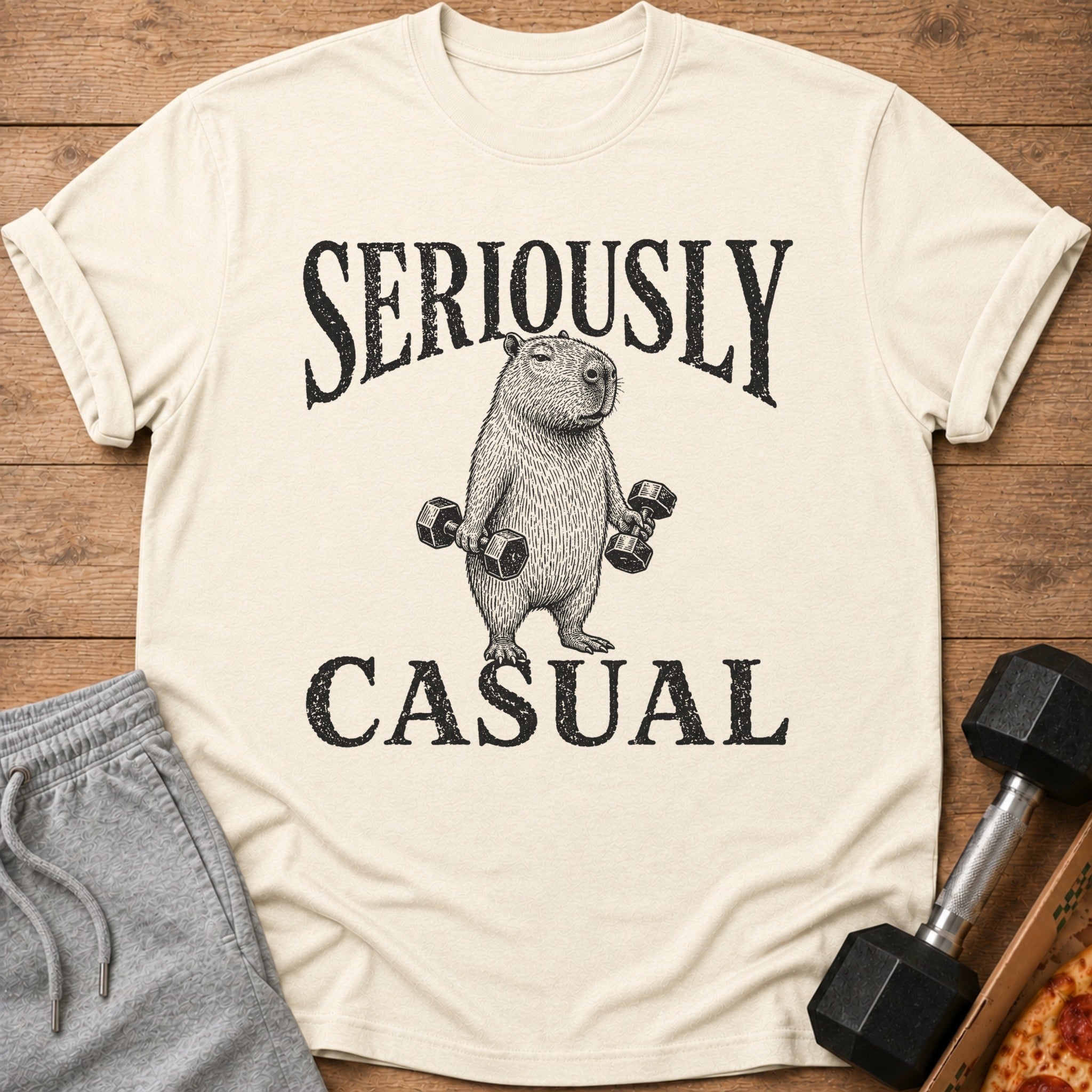Cream t-shirt with a capybara holding dumbbells and text "SERIOUSLY CASUAL".