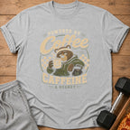 Grey t-shirt graphic featuring a tired bear drinking coffee, text "Powered by Coffee, Caffeine & Regret".