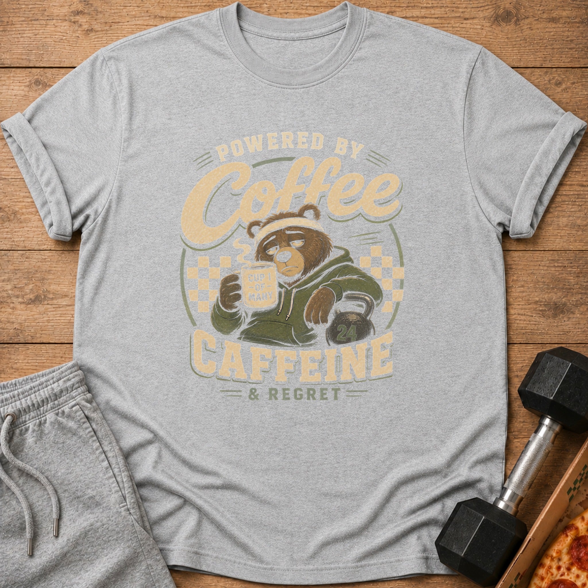 Grey t-shirt graphic featuring a tired bear drinking coffee, text "Powered by Coffee, Caffeine & Regret".