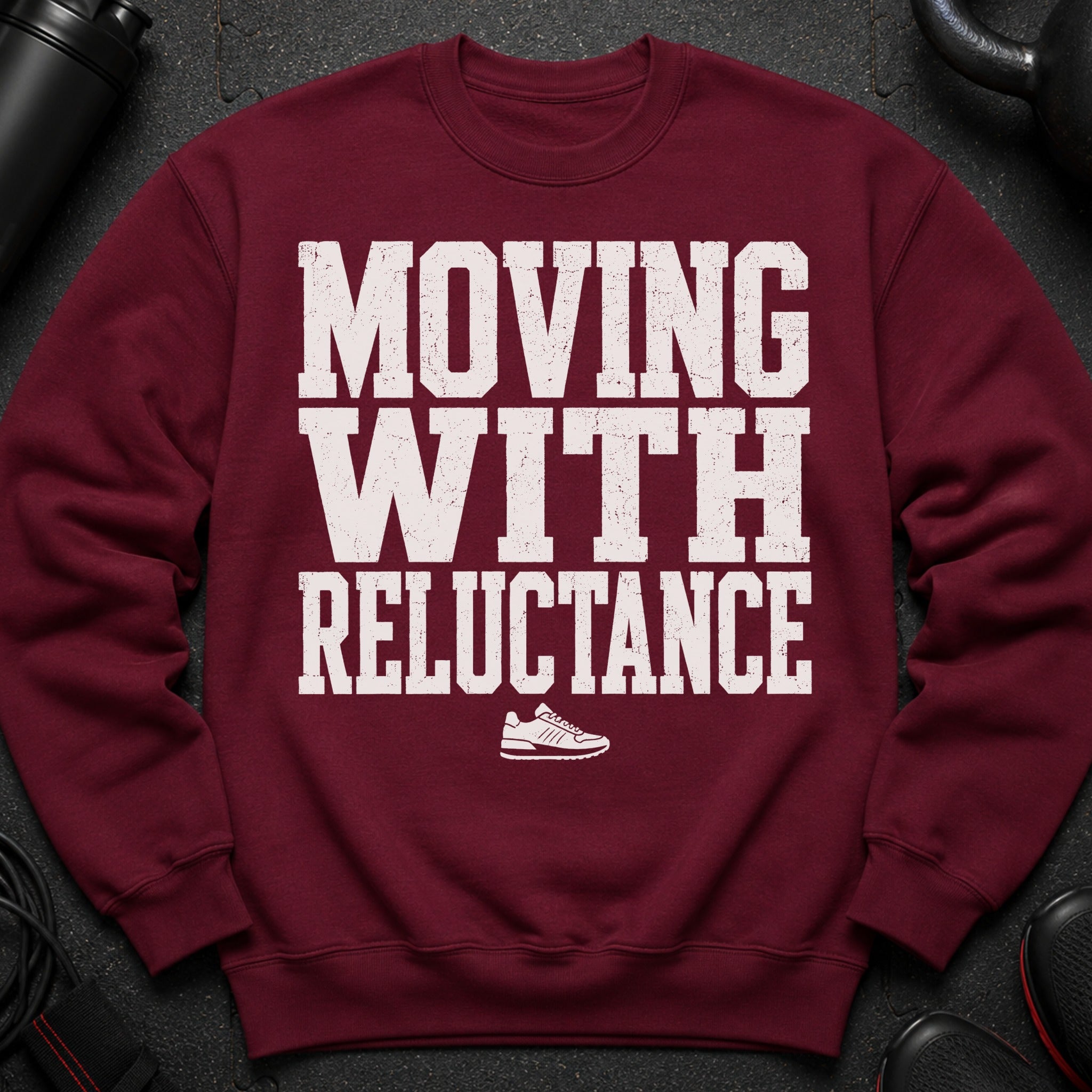 Maroon sweatshirt with white distressed text "MOVING WITH RELUCTANCE" and a sneaker graphic.