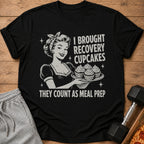 Black t-shirt with vintage woman holding cupcakes, text reads "I BROUGHT RECOVERY CUPCAKES THEY COUNT AS MEAL PREP".