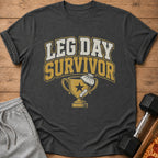 Dark gray t-shirt with "LEG DAY SURVIVOR" text and trophy graphic.