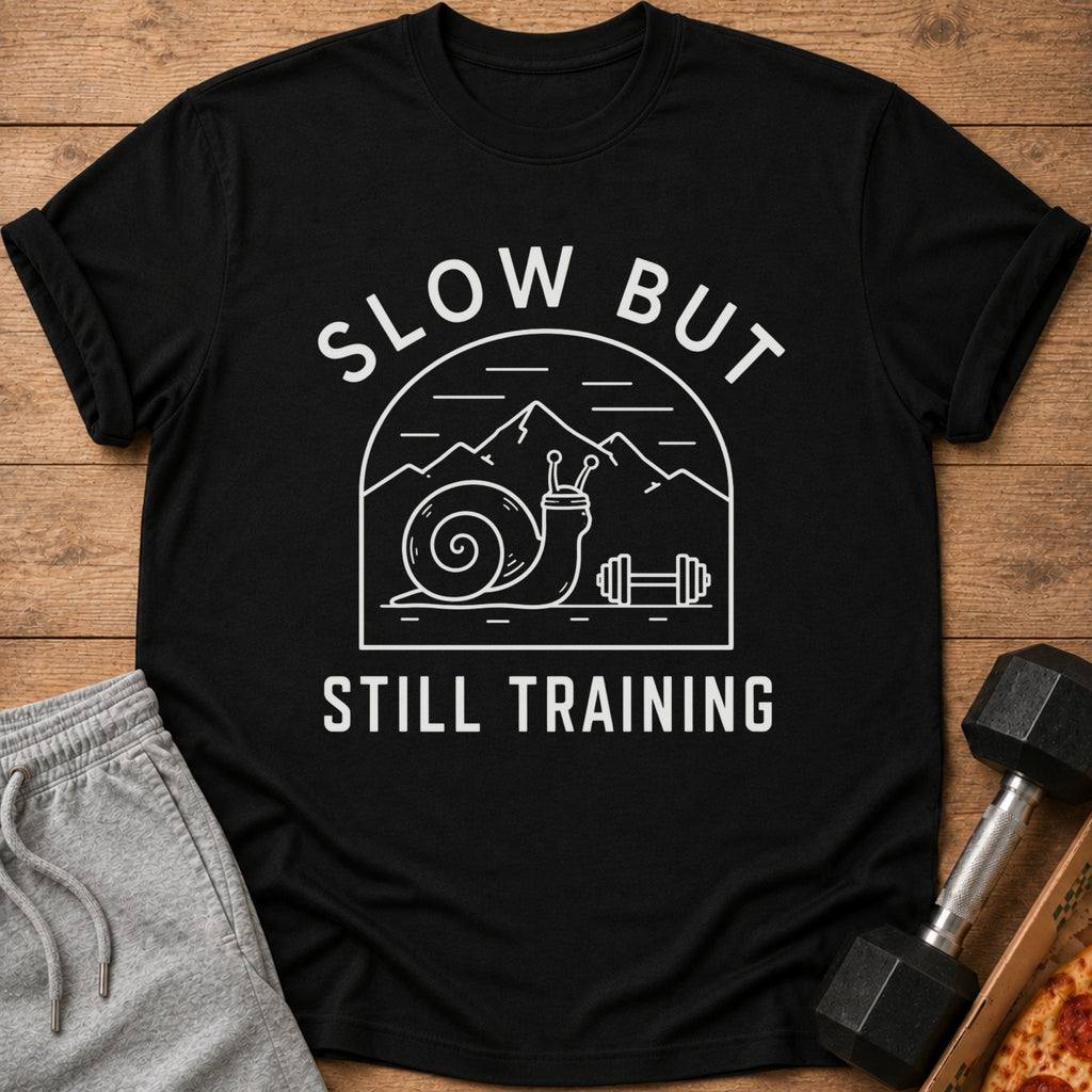 Black t-shirt with white text and graphics of a snail and mountains, reading "SLOW BUT STILL TRAINING".