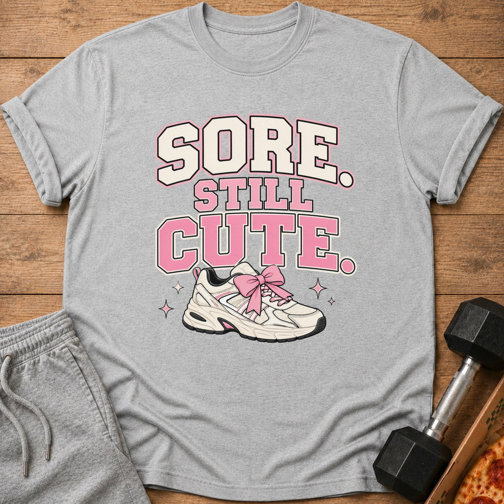 Grey t-shirt with "Sore Still Cute" text and a sneaker with pink bow.