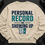 Light beige sweatshirt with "Personal Record In Showing Up" text and workout icons.