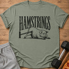 Green t-shirt with black text "HAMSTRINGS" and a pig stretching on a bar.