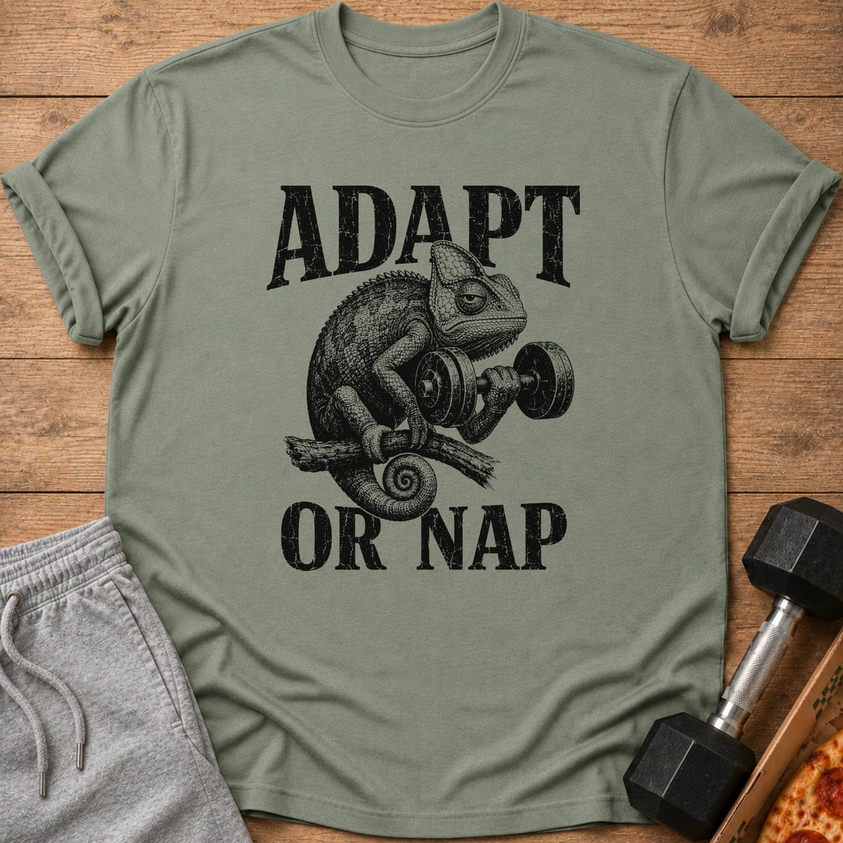 T-shirt with a distressed graphic of a chameleon lifting a dumbbell, text reads "ADAPT OR NAP."