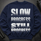 Navy sweatshirt with white textured text that reads "SLOW PROGRESS STILL PROGRESS".