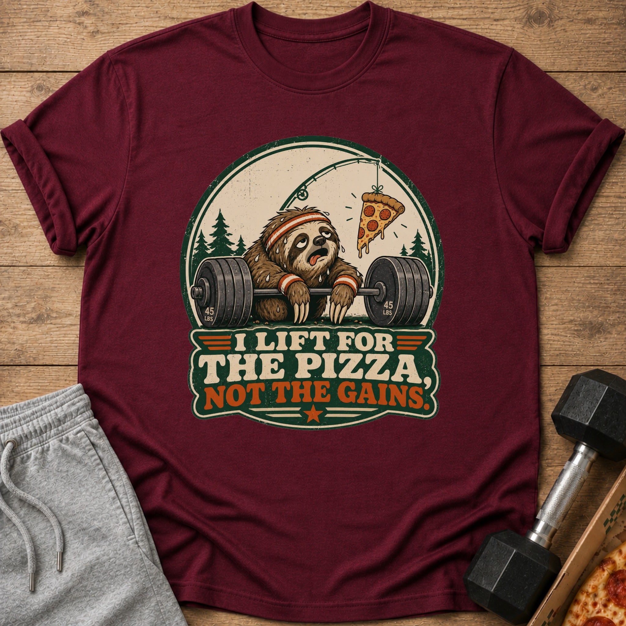 Maroon t-shirt with graphic of sloth lifting weights and pizza on a string. Text: "I lift for the pizza, not the gains."
