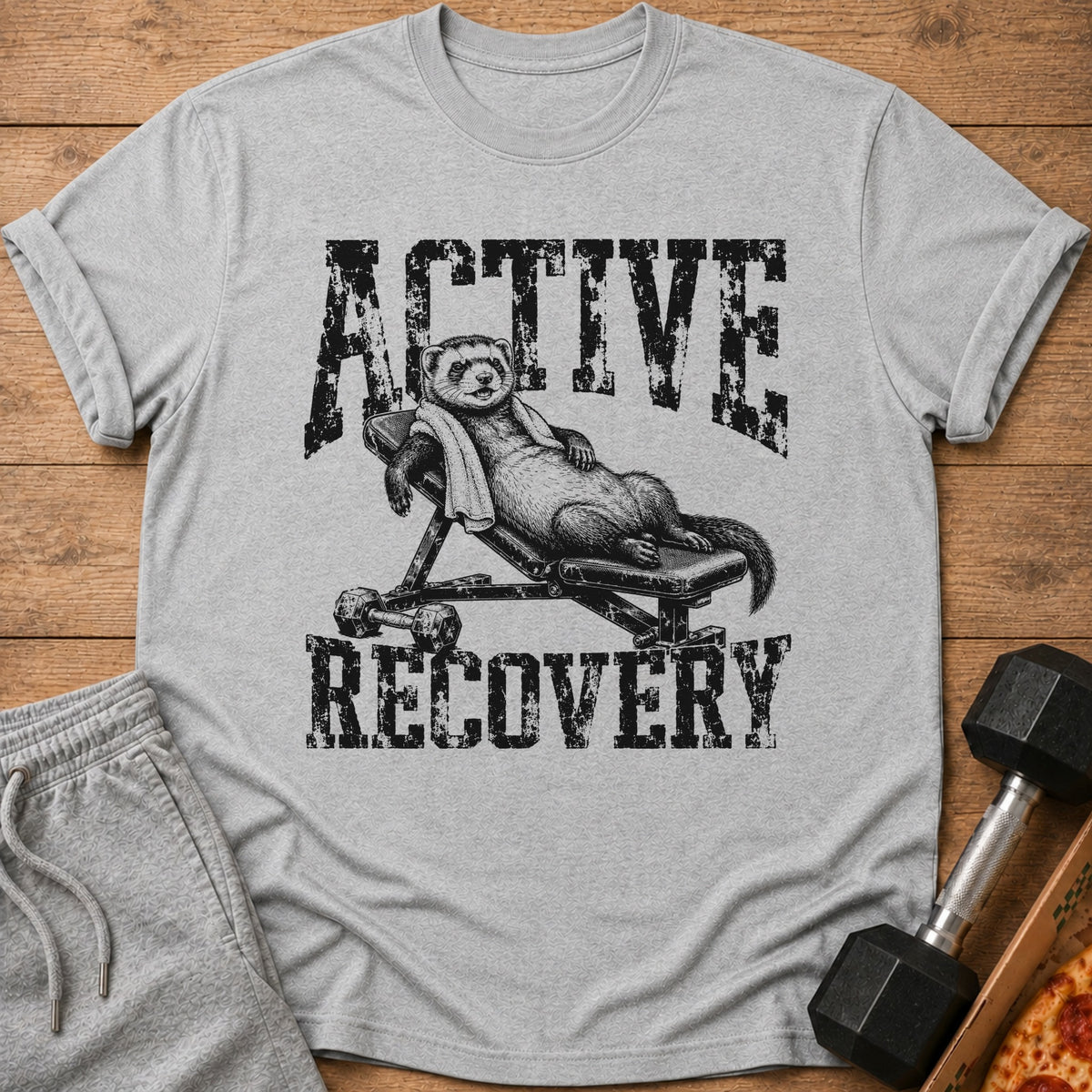 Ferret resting on a weight bench with dumbbells and pizza, text reads ACTIVE RECOVERY.