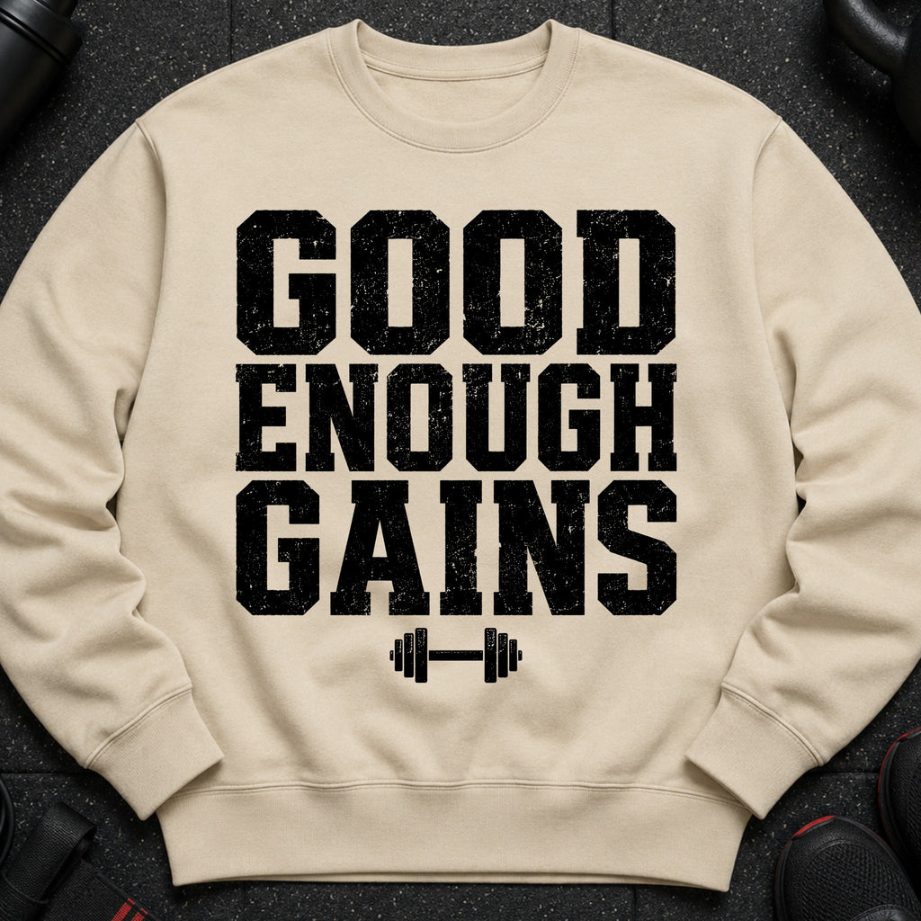 Light tan crewneck sweatshirt with black text "GOOD ENOUGH GAINS" and dumbbell graphic.