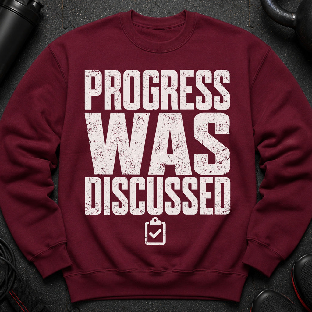 Maroon sweatshirt with distressed white text: PROGRESS WAS DISCUSSED.