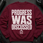 Maroon sweatshirt with distressed white text: PROGRESS WAS DISCUSSED.