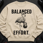 Cream sweatshirt with a flamingo holding a kettlebell and text "BALANCED EFFORT."