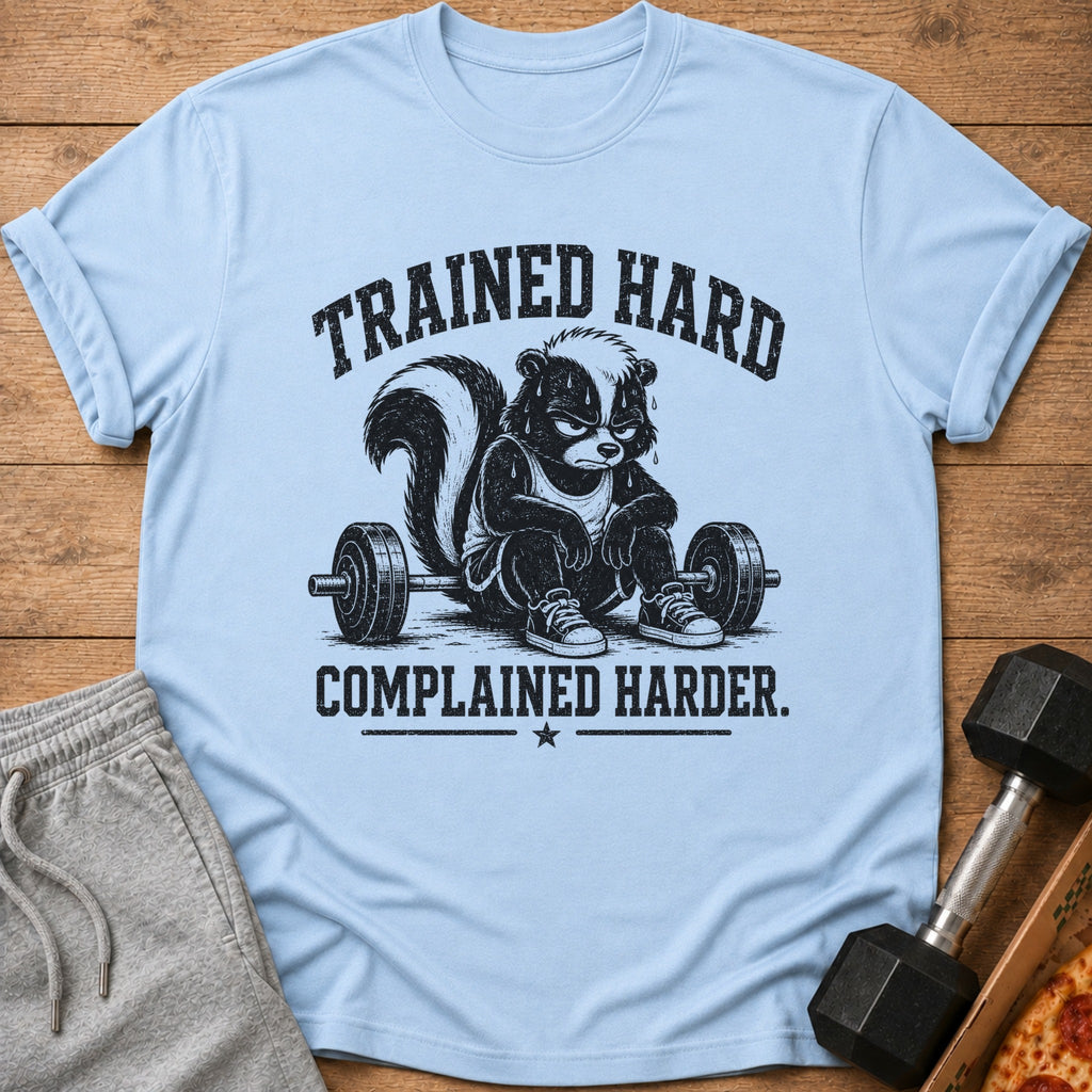 Light blue t-shirt with a skunk lifting weights and text "TRAINED HARD COMPLAINED HARDER."