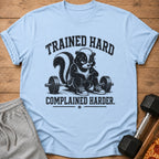 Light blue t-shirt with a skunk lifting weights and text "TRAINED HARD COMPLAINED HARDER."