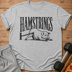 Gray t-shirt with distressed "HAMSTRINGS" text above a cartoon pig doing a hamstring stretch.