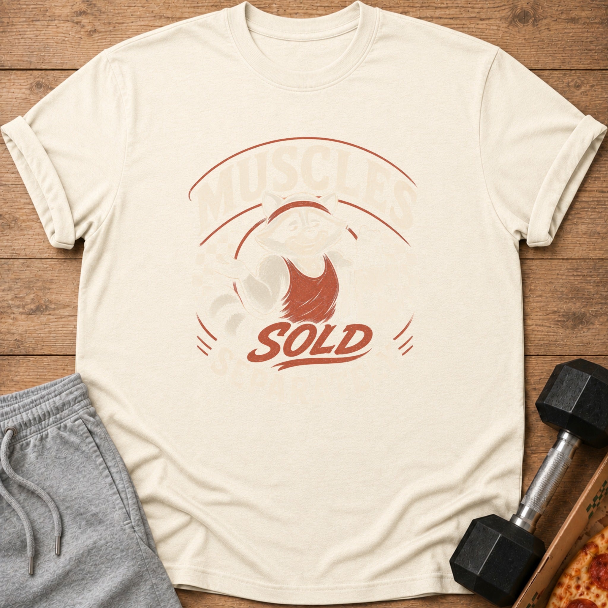 Cream t-shirt with a raccoon in a tank top and text "MUSCLES" and "SOLD".