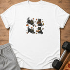 White t-shirt with four cartoon black cats engaged in fall-themed activities.