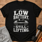 Black t-shirt with "Low Battery. Still Lifting." text and dumbbell graphic.