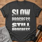 Dark gray t-shirt with white text reading "SLOW PROGRESS STILL PROGRESS".