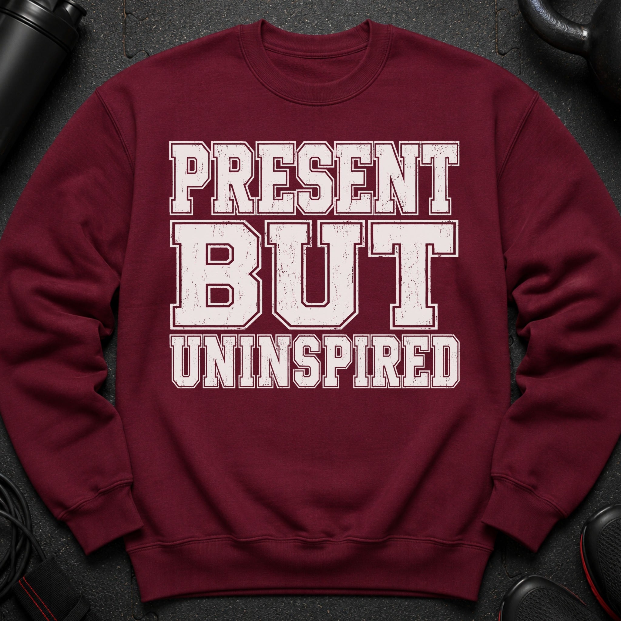 Maroon sweatshirt with "PRESENT BUT UNINSPIRED" text in distressed white lettering.