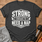 Dark grey t-shirt with white text reading "STRONG ENOUGH TO NEED A NAP".