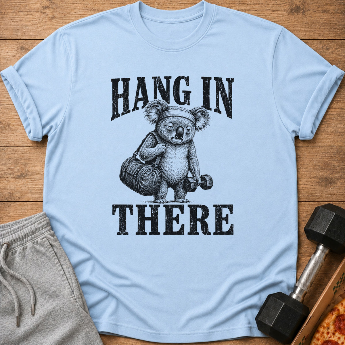 Light blue t-shirt with koala lifting weights and text "HANG IN THERE".