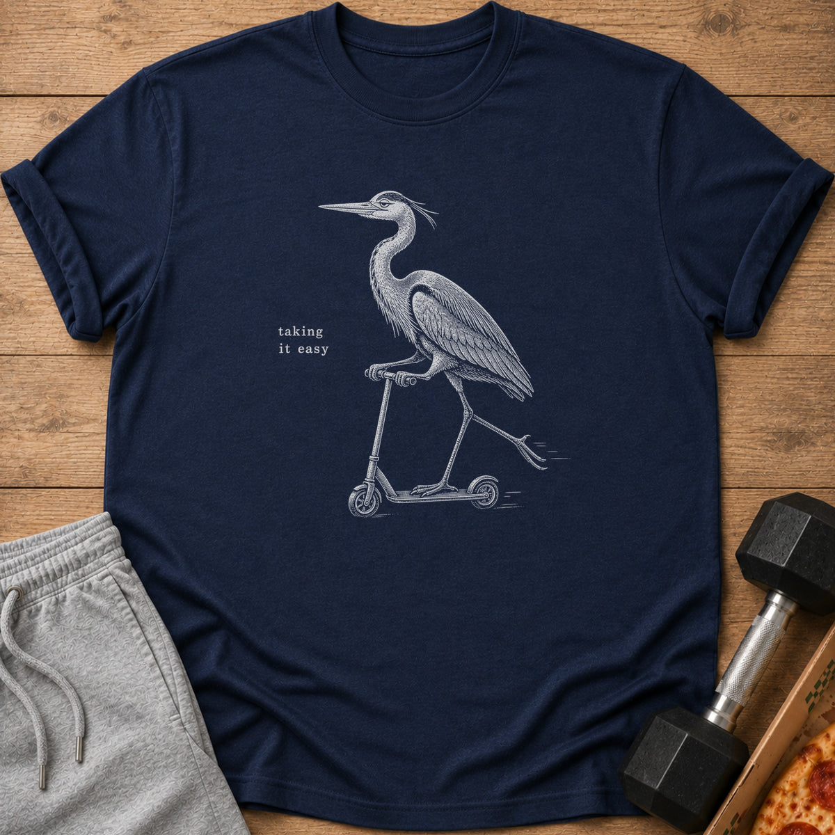 Navy t-shirt with a drawing of a heron riding a scooter and the text "taking it easy".