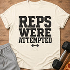 Cream t-shirt with "REPS WERE ATTEMPTED" text and barbell graphic.