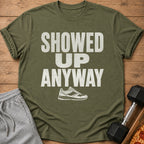 Olive t-shirt with distressed white text "SHOWED UP ANYWAY" and a sneaker graphic.