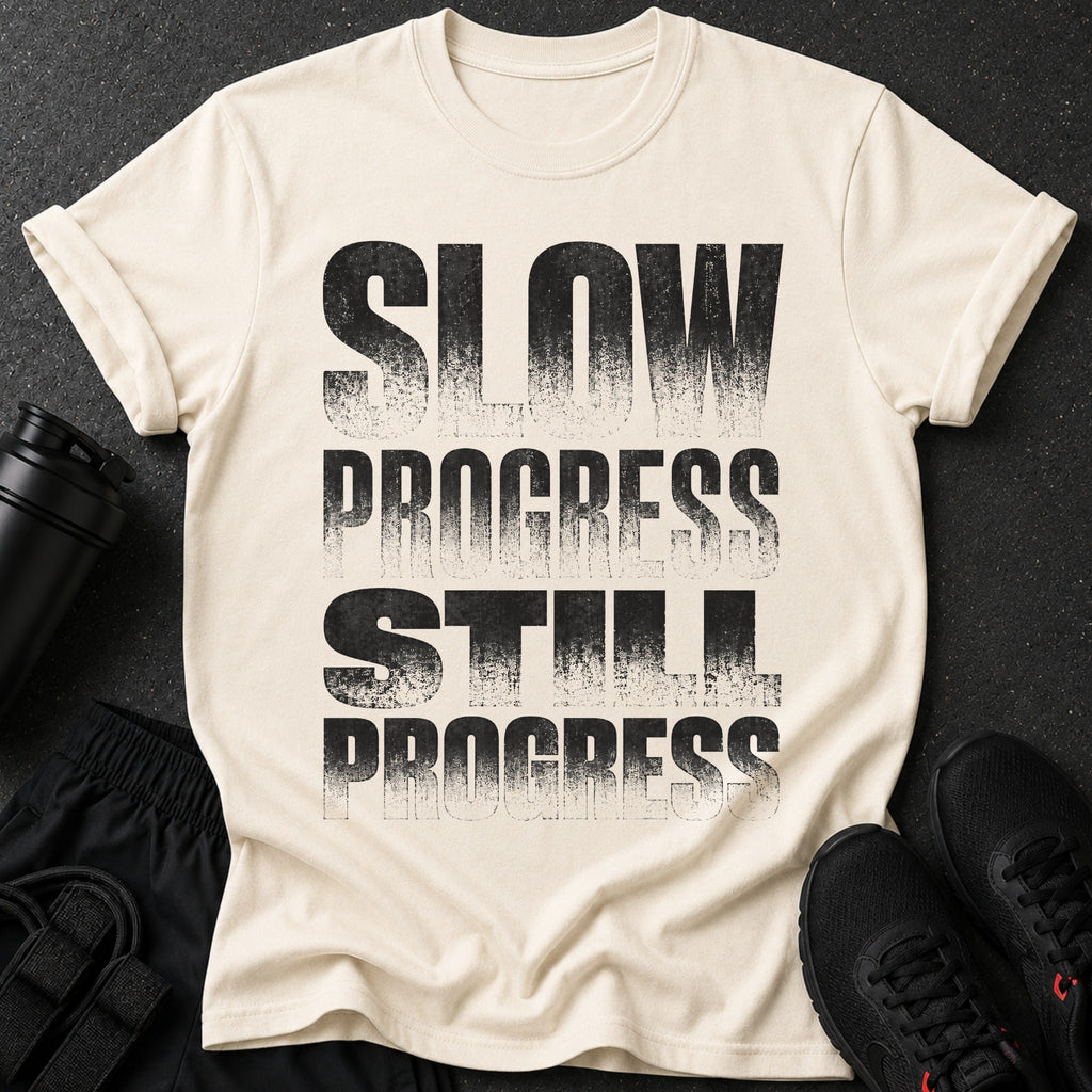 Cream t-shirt with distressed black text reading "SLOW PROGRESS STILL PROGRESS".