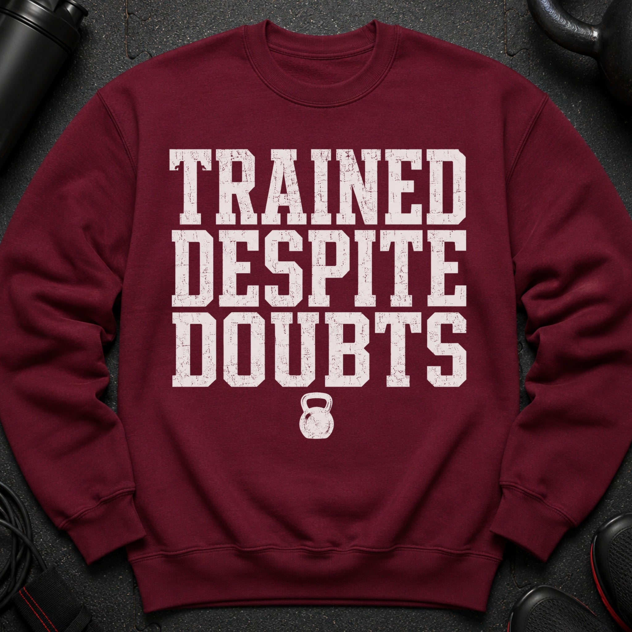 Maroon sweatshirt with "TRAINED DESPITE DOUBTS" text and kettlebell graphic.