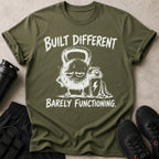 Green t-shirt with "BUILT DIFFERENT BARELY FUNCTIONING" text and a cartoon kettlebell.