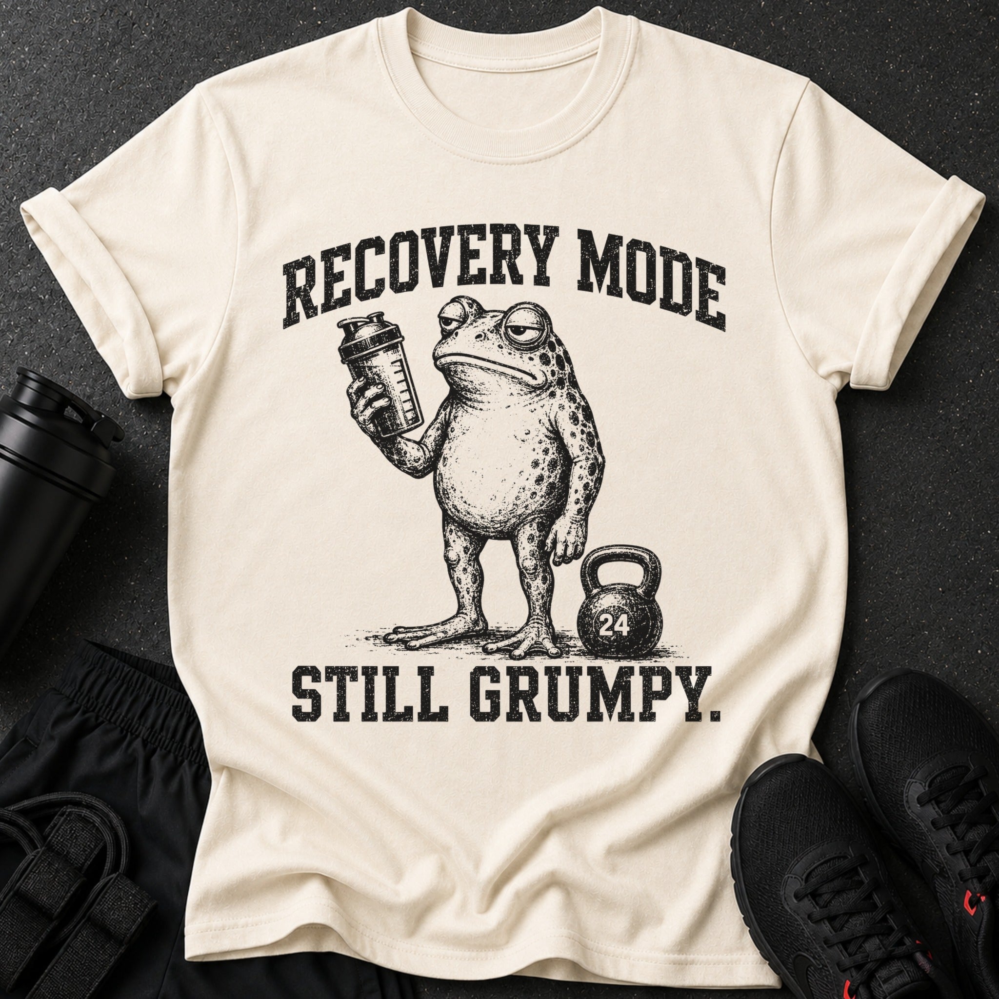 T-shirt with grumpy frog, shaker, and kettlebell. Text reads "RECOVERY MODE STILL GRUMPY."