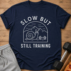 Navy t-shirt with "Slow But Still Training" text and a snail lifting weights design.