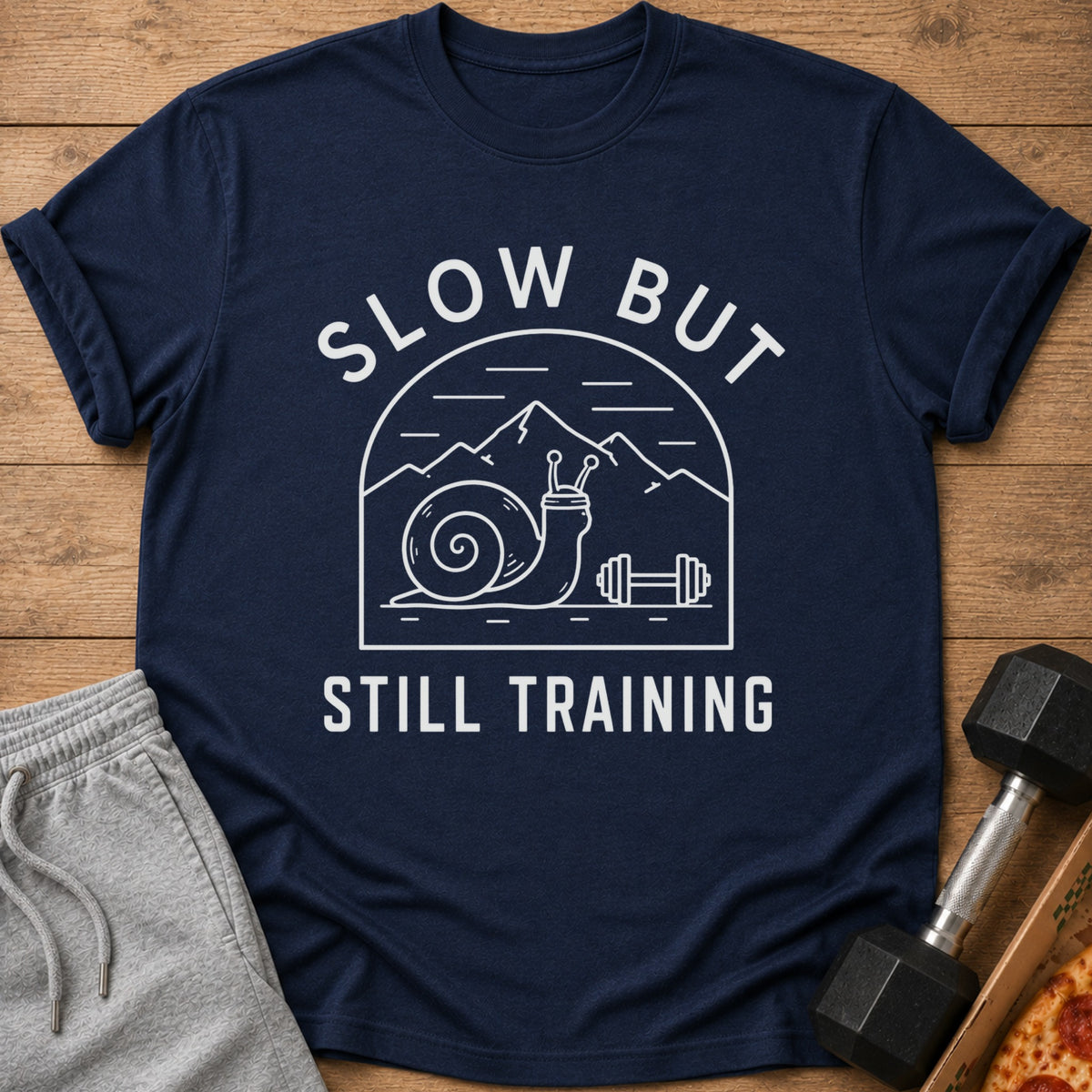 Navy t-shirt with "Slow But Still Training" text and a snail lifting weights design.