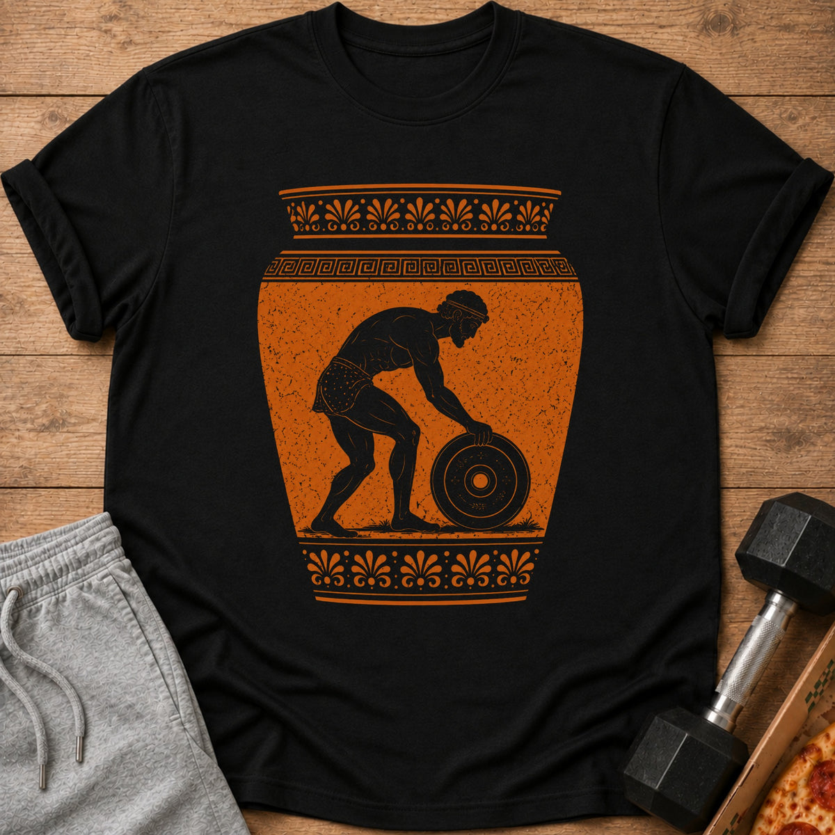 Black t-shirt with orange ancient Greek style design of a man lifting a weight.