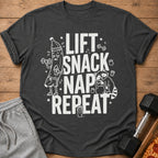 T-shirt with "Lift Snack Nap Repeat" text, cartoon banana lifting weights, sleeping raccoon.