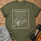 Olive green t-shirt with "Postage Paid, Energy Pending" stamp design.