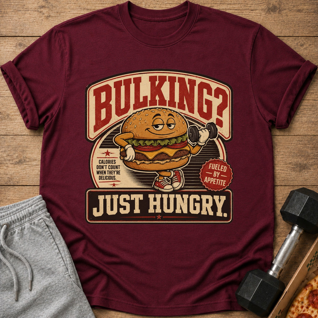 Maroon t-shirt with cartoon burger lifting dumbbell and text "BULKING? JUST HUNGRY."